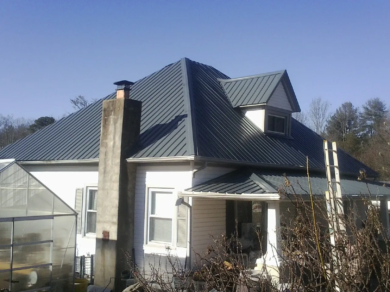 Dark blue standing seam metal roof on a white farmhouse with dormer — Slate & Tile Roof Repair by Roofing Brothers in Greens Fork