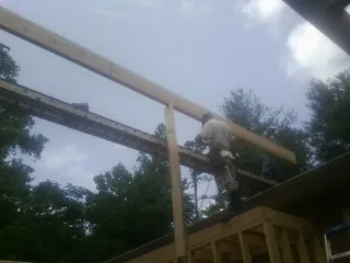 Carpenter setting a ridge beam over a new addition frame — Ice Dam Removal by Roofing Brothers in Greens Fork