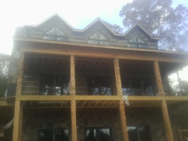Dormers and porch framing on a large log home under construction — Roof Coating work by our crew in Greens Fork