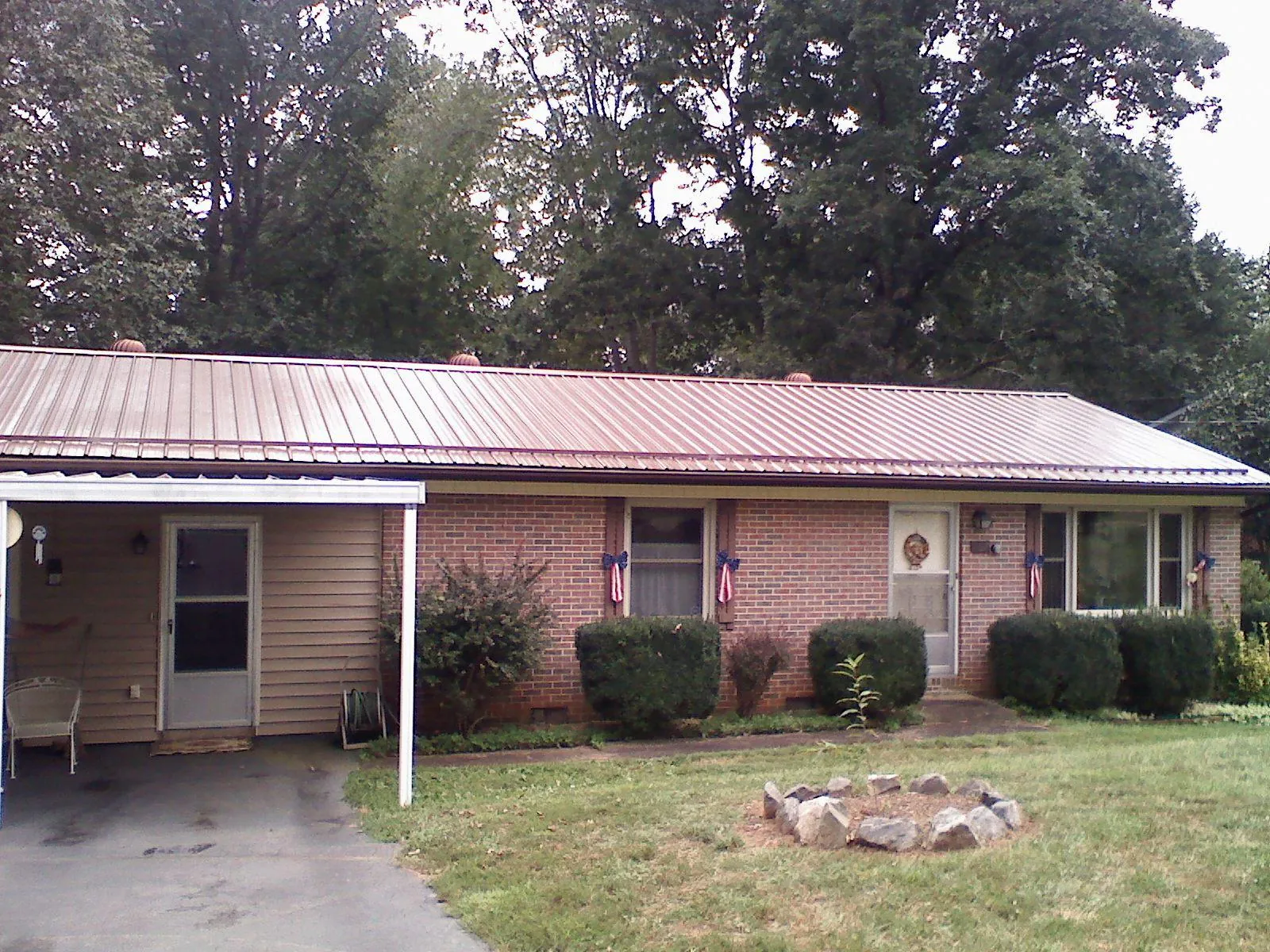 Bronze metal roof and carport on a brick ranch home — Roof Repair work by our crew in Greens Fork